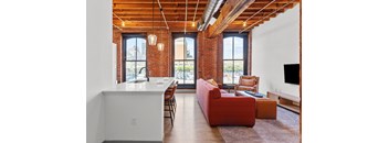 A living room with a red couch and a white kitchen island.