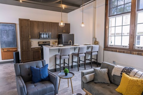 a living room with a kitchen with a bar and couches