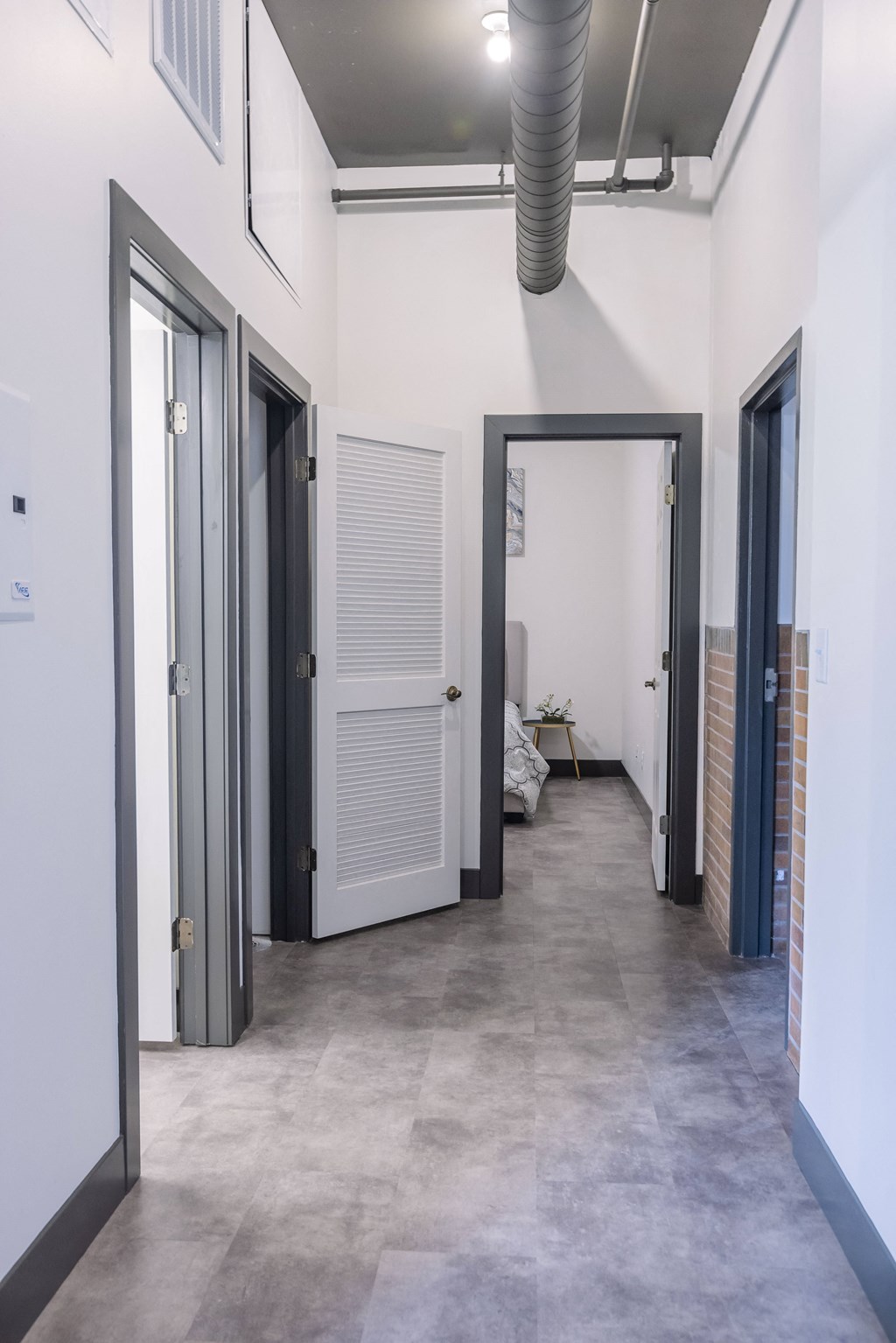 a hallway with doors in a building with white walls and concrete floors