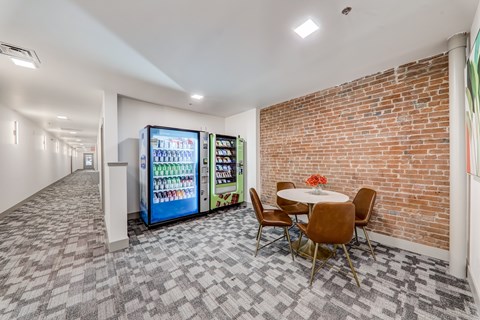 A room with a brick wall and a fridge with drinks in it.