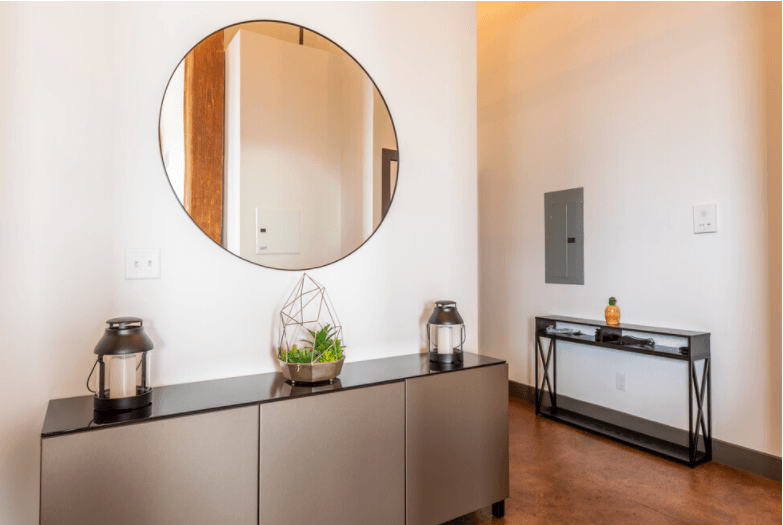 a large mirror on a wall in a room with a cabinet