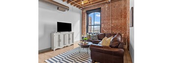 A living room with a brown leather couch and a white cabinet with a flat screen TV on it.