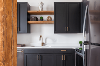 a kitchen with black cabinets and stainless steel appliances and wooden shelves