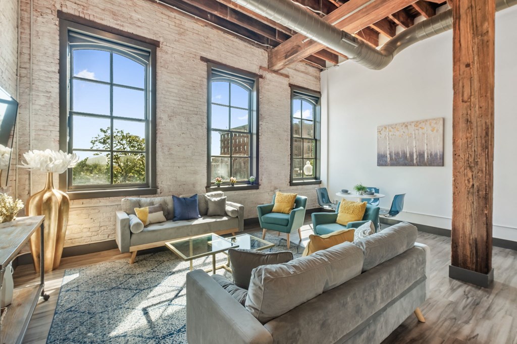 a living room with couches and chairs and large windows