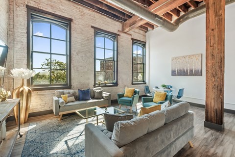 a living room with couches and chairs and large windows