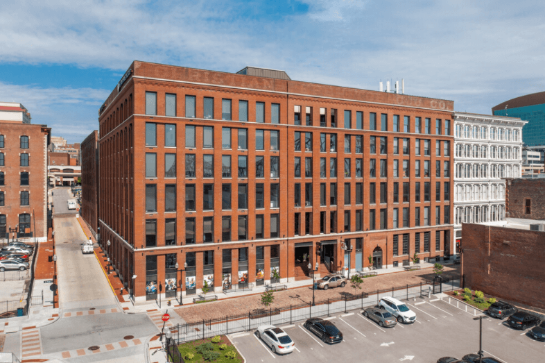 a large brick building with many windows and a parking lot in front of it