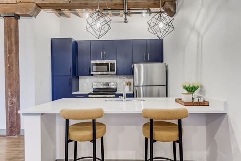 a kitchen with blue cabinets and a counter with two stools