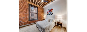 A bedroom with a brick wall and a bed.
