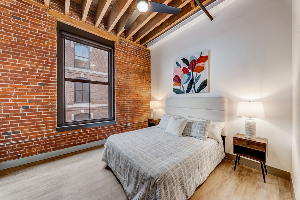 a bedroom with a bed and a brick wall