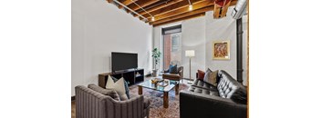 A living room with a black leather couch and a striped armchair.