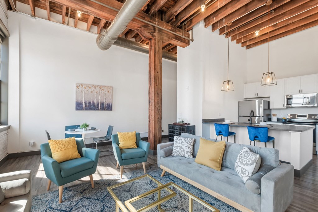 a living room with a couch and chairs and a kitchen
