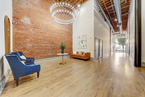 A blue chair sits in a room with a brick wall and a chandelier.