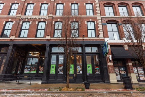 A building with a black awning and a tree in front of it.
