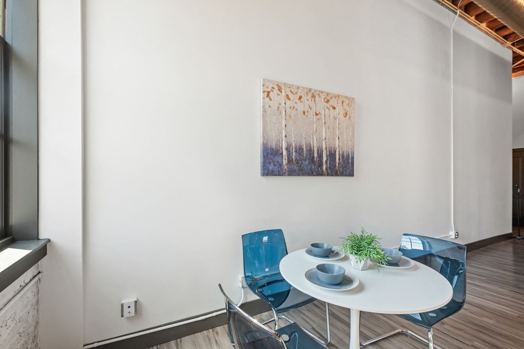 a dining area with a table and chairs and a painting on the wall