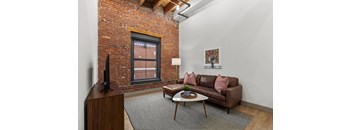 A living room with a brown couch and a TV on a wooden stand.