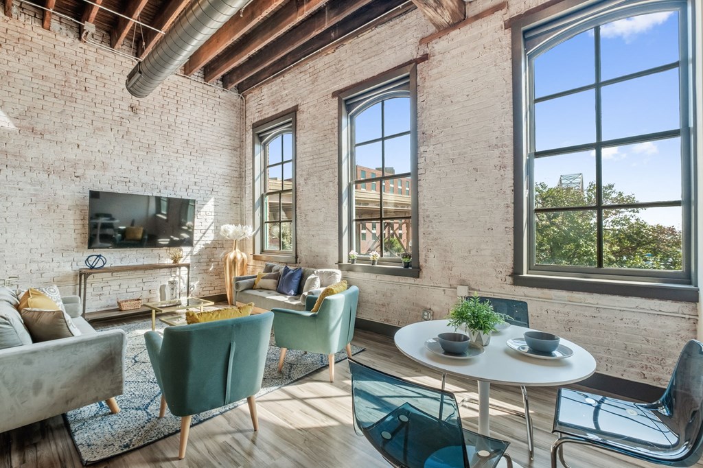 a living room with a table and chairs and large windows