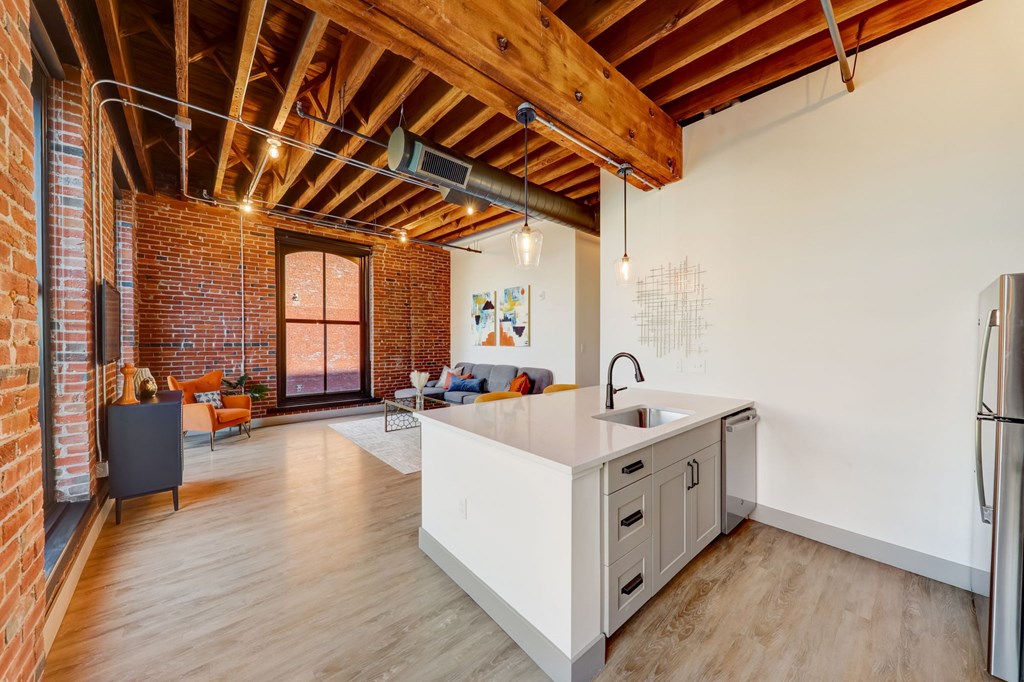 a kitchen with a white counter top in a room with a exposed brick wall at Greeley Lofts, St. Louis, Missouri