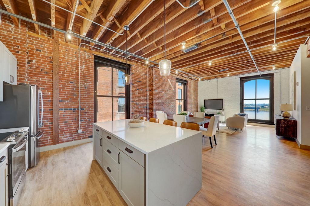 a kitchen and living room with exposed brick walls and a white counter top at Greeley Lofts, St. Louis, MO, 63102