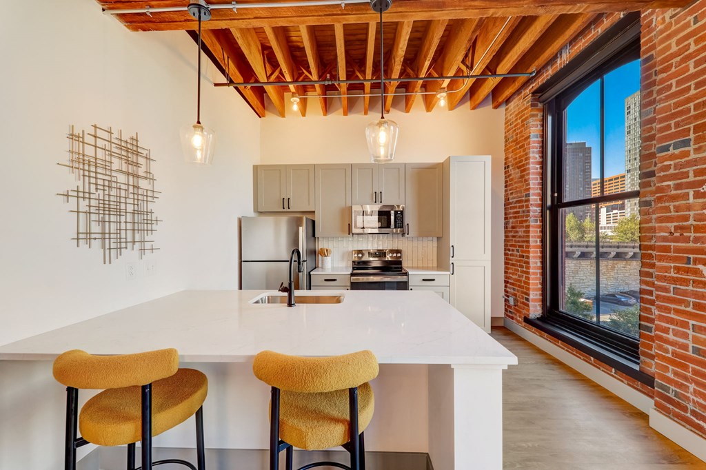 a kitchen with a white counter top and a large window at Greeley Lofts, St. Louis, MO, 63102
