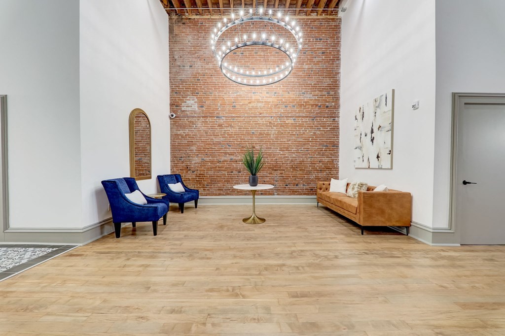 a living room with blue chairs and a brick wall at Greeley Lofts, St. Louis, MO