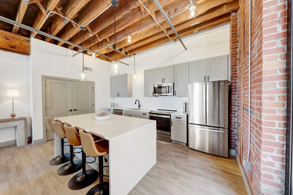 a kitchen with a white island and a stainless steel refrigerator at Greeley Lofts, Missouri