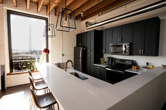 a kitchen with black cabinets and a large window