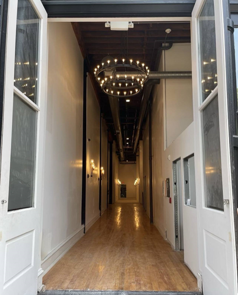 A long hallway with lights on the ceiling and doors on both sides.