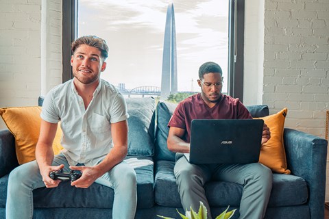 two men sitting on a couch playing video games