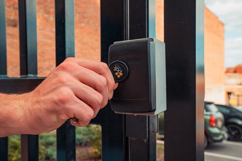 a hand is unlocking a gate with a digital lock