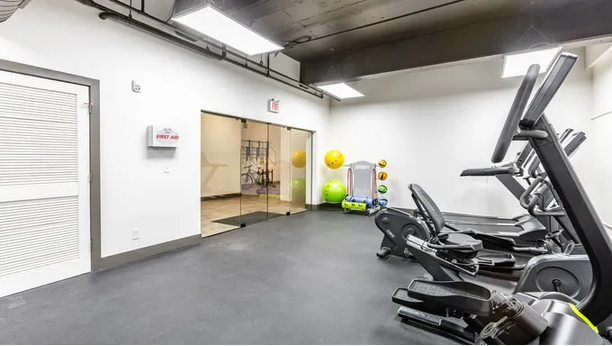 a gym with cardio equipment and a yellow ball in the background