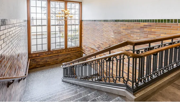 a stairway in a church with a large window and a cross on the wall