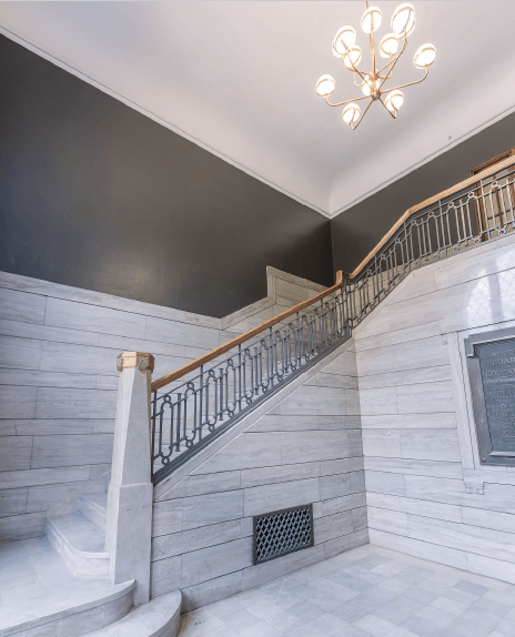 a staircase in a building with white marble walls and a chandelier