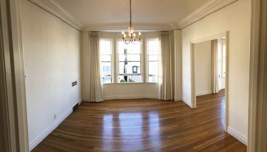 an empty living room with wood floors and a window