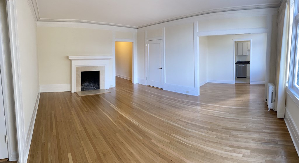 an empty living room with a fireplace and wooden floors