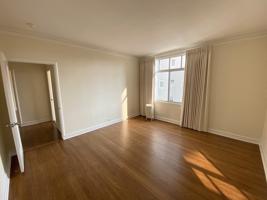 an empty living room with wooden floors and a window