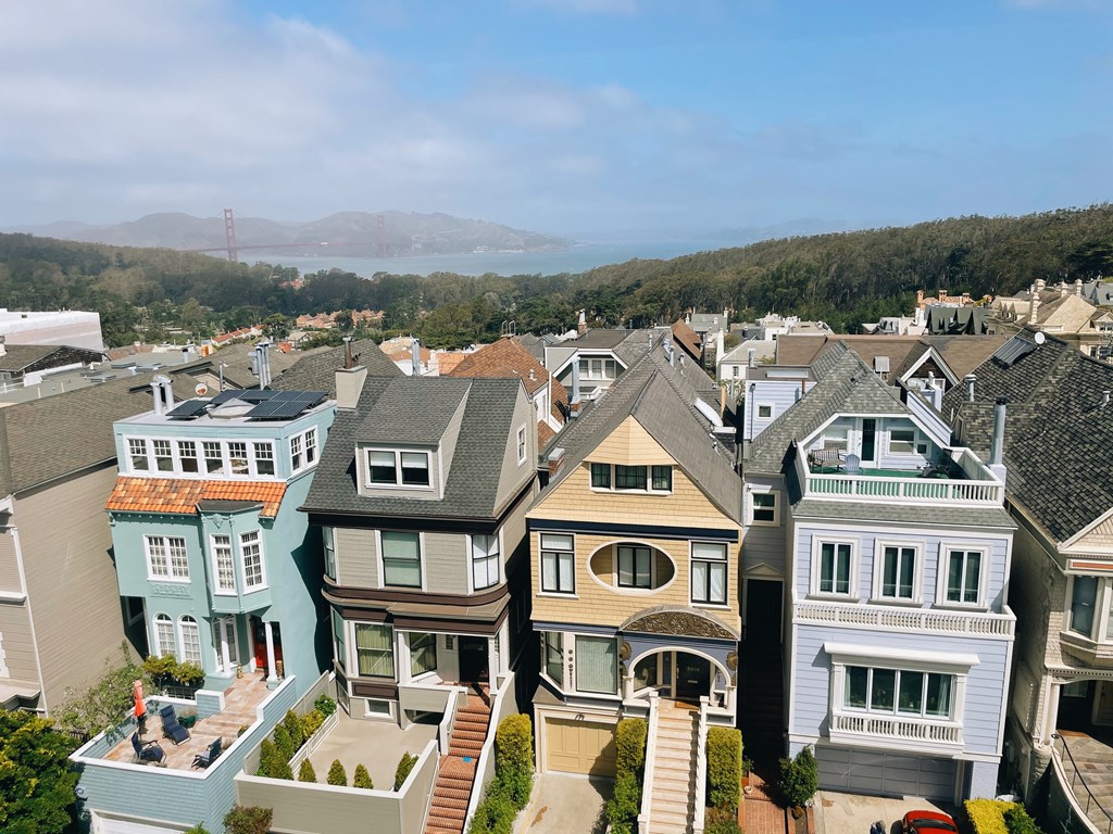 an aerial view of a neighborhood with houses and the golden gate bridge in the background