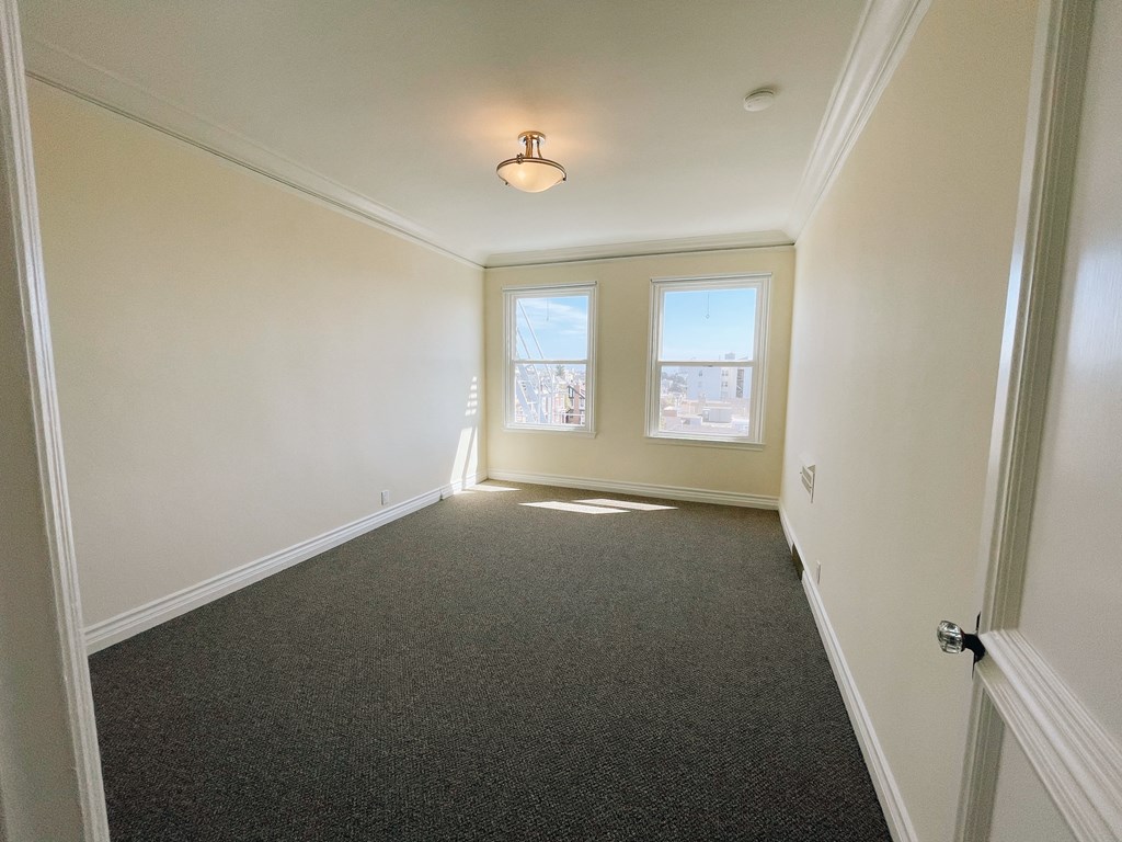 an empty room with a carpeted floor and two windows