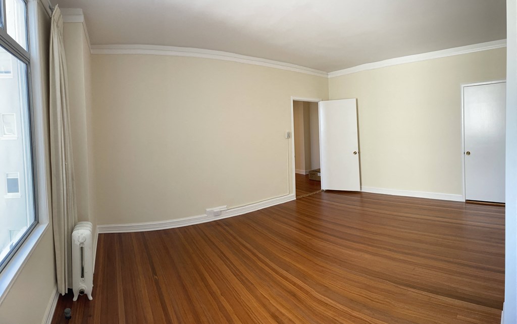 an empty living room with wooden floors and white walls