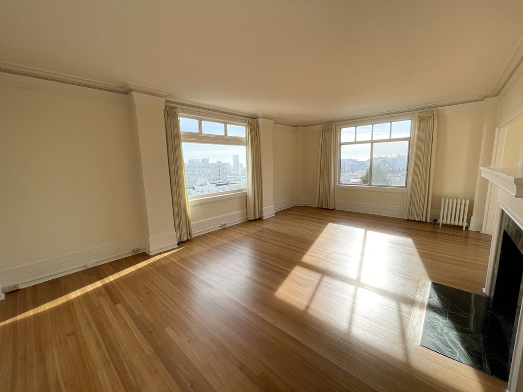 an empty living room with wooden floors and windows