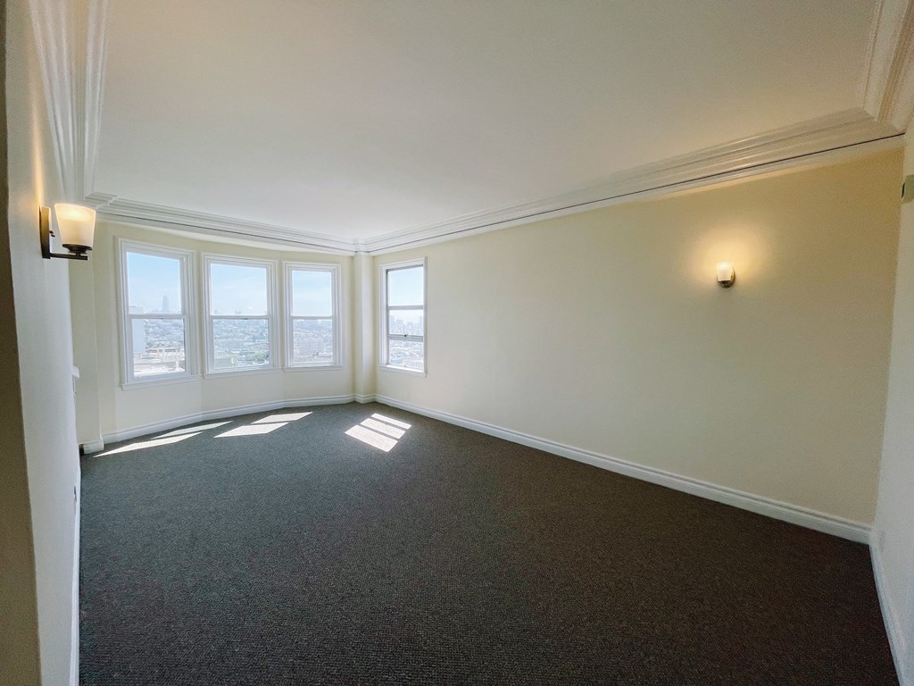 an empty living room with windows and a carpet