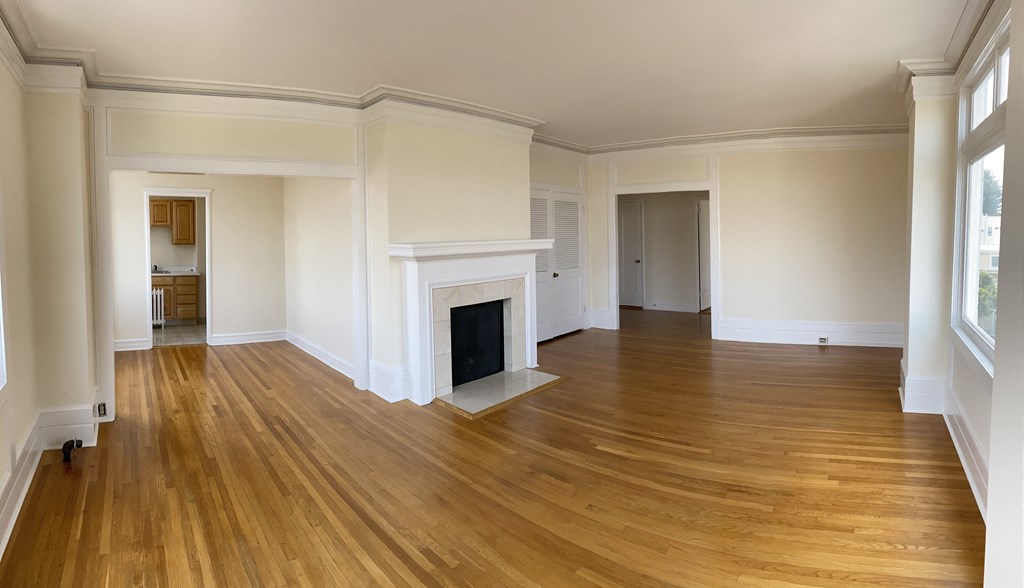an empty living room with a fireplace and wooden floors