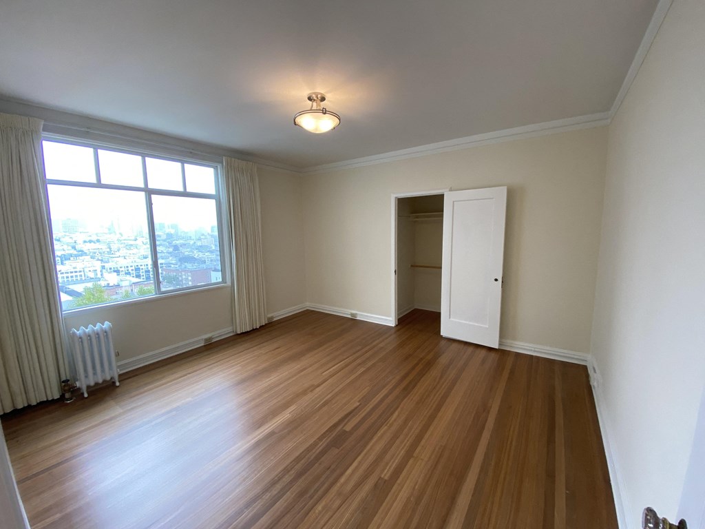an empty living room with wood floors and a window