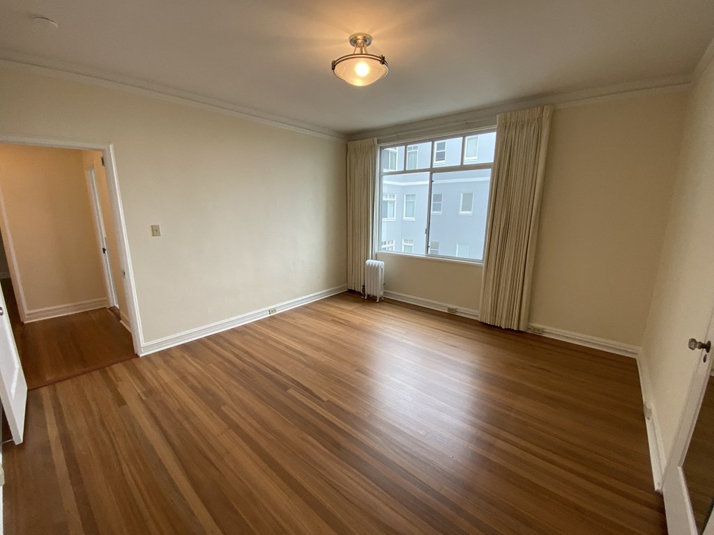 an empty living room with wooden floors and a window