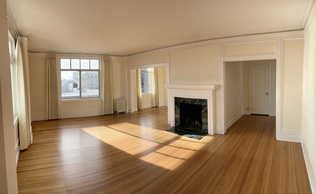 an empty living room with a fireplace and wooden floors