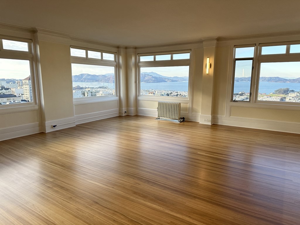 an empty living room with a hard wood floor and windows