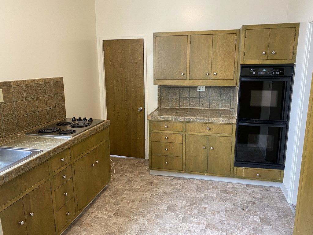 a kitchen with wooden cabinets and a black oven and sink