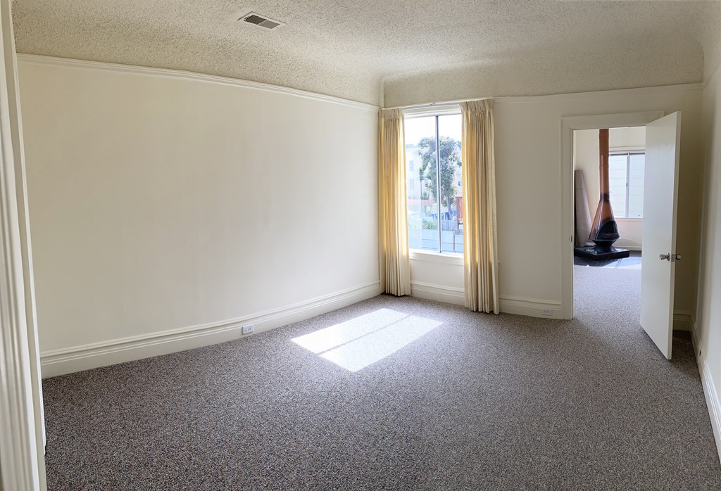 an empty living room with a large window and carpet