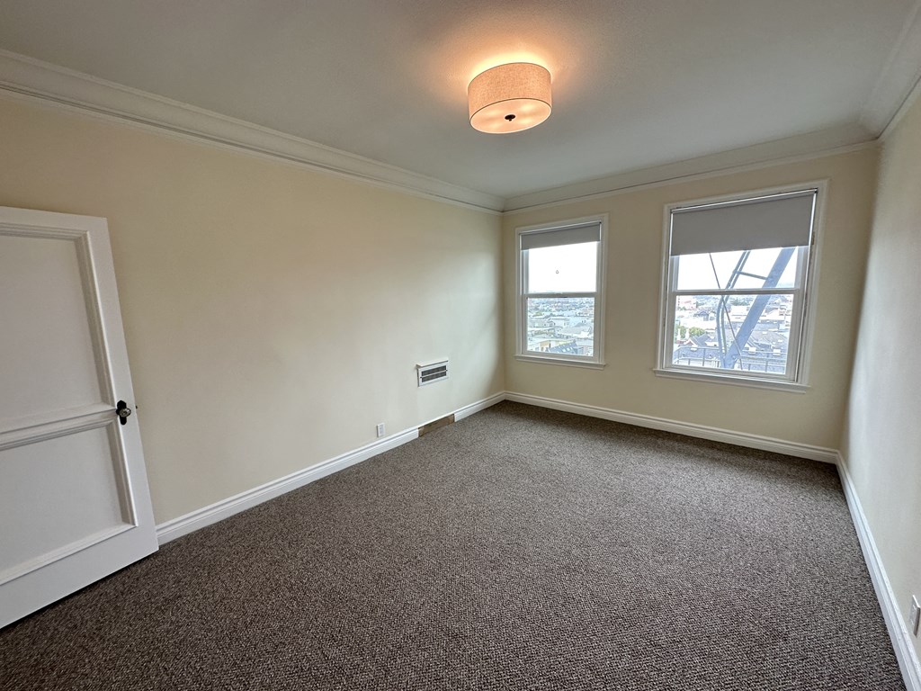 an empty living room with a door and two windows
