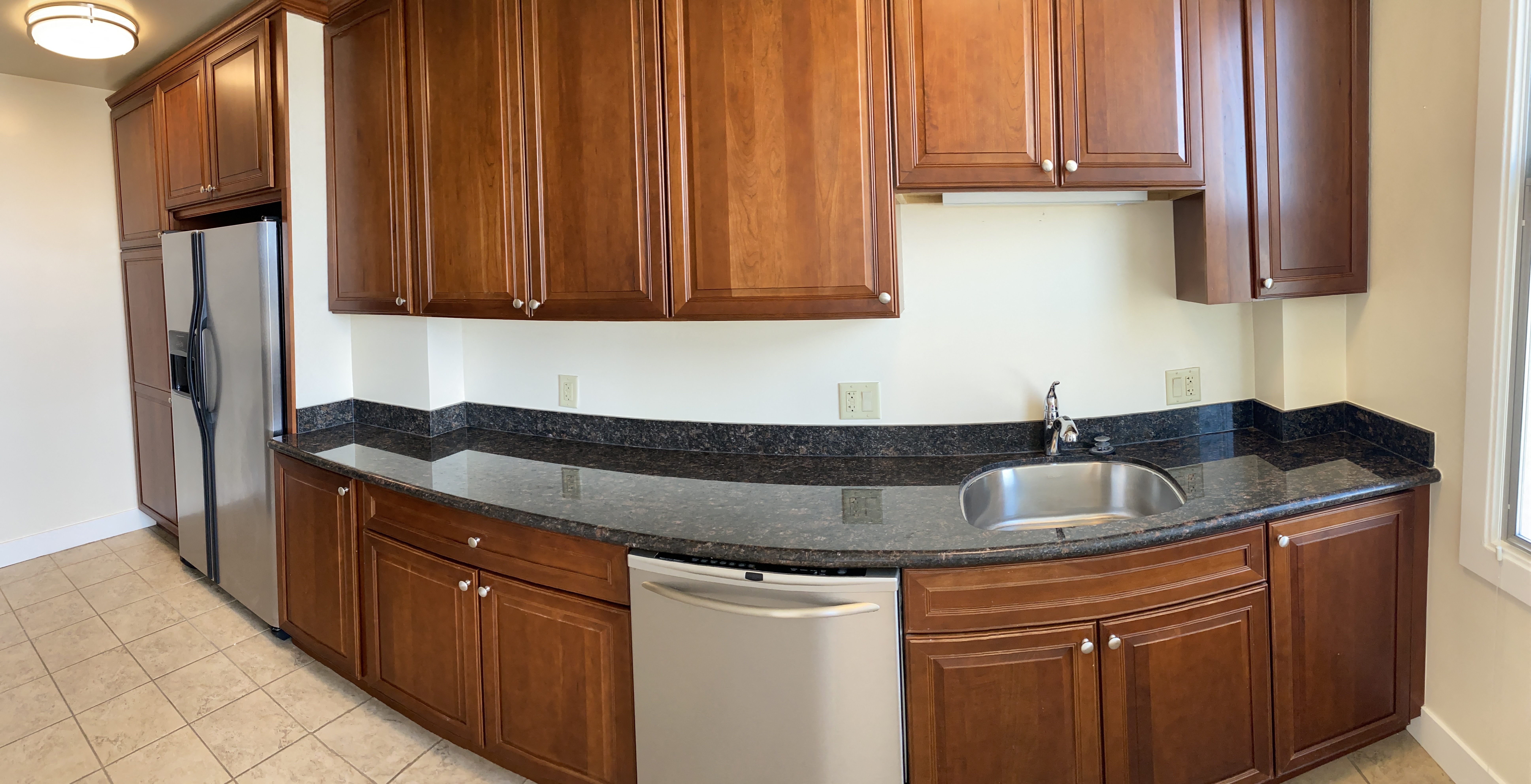 a kitchen with wooden cabinets and a stainless steel dishwasher