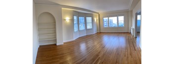 an empty living room with a hard wood floor and white walls